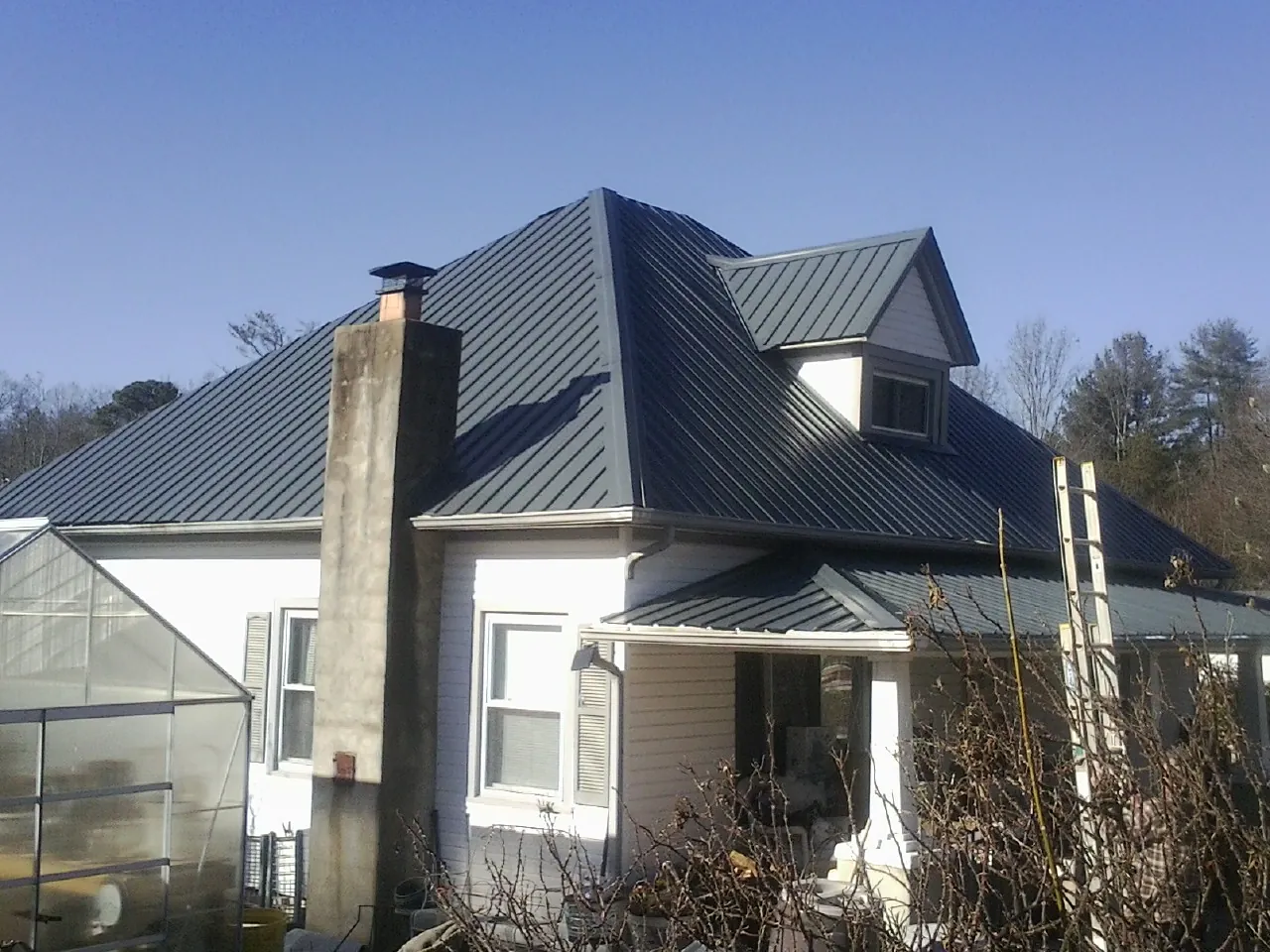 Dark blue standing seam metal roof on a white farmhouse with dormer — Slate & Tile Roof Repair by Roofing Brothers in Hoffman