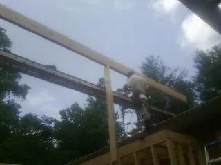 Carpenter setting a ridge beam over a new addition frame — Ice Dam Removal by Roofing Brothers in Hoffman