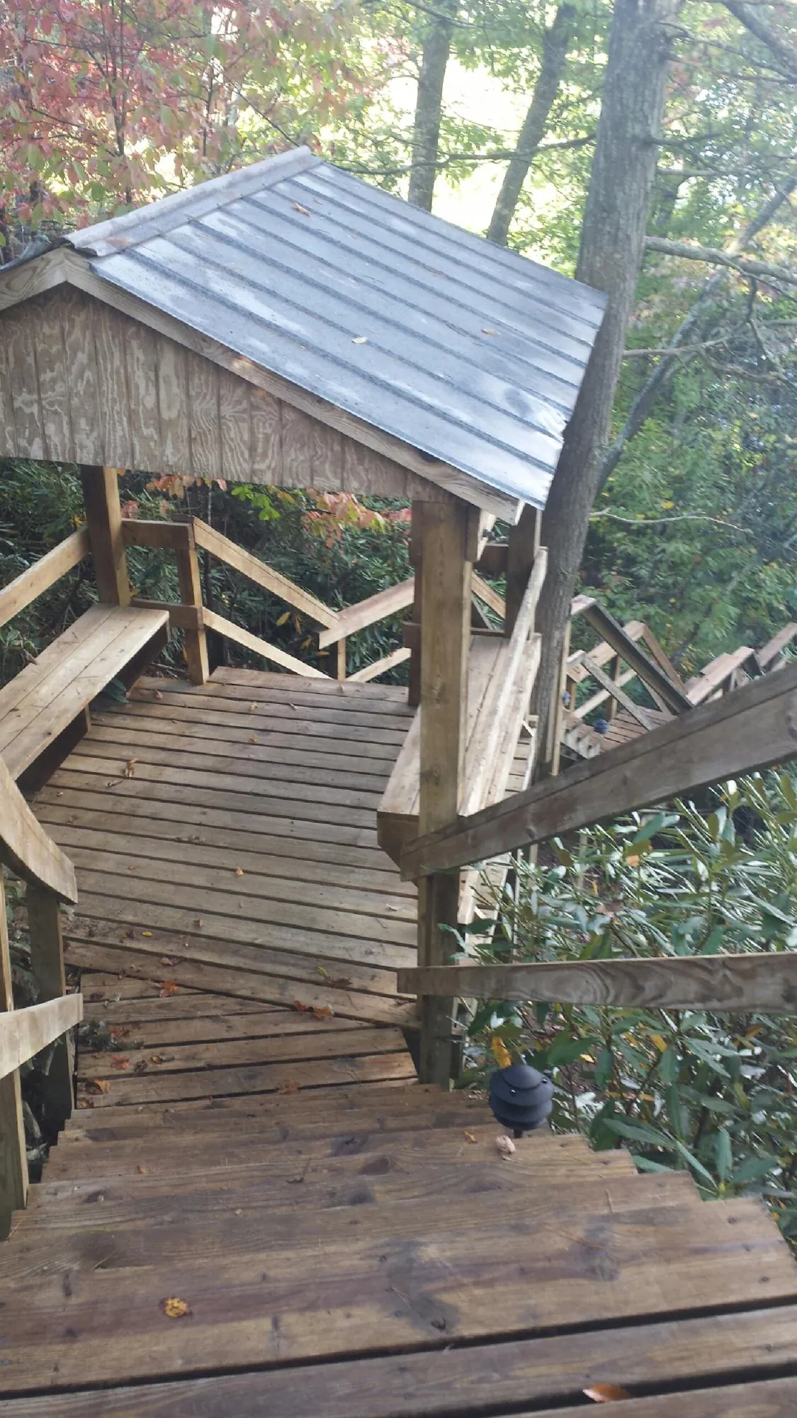 Metal roofed shelter over wooden steps on a wooded walkway — Skylight Repair & Installation work by our crew in Hoffman