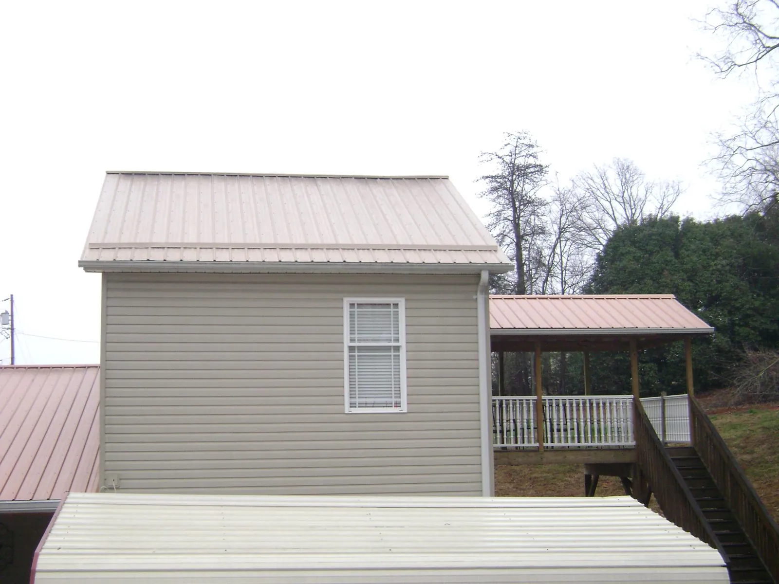 Tan metal roofs on a two story addition and attached porch, from a Roof Replacement job in Hoffman